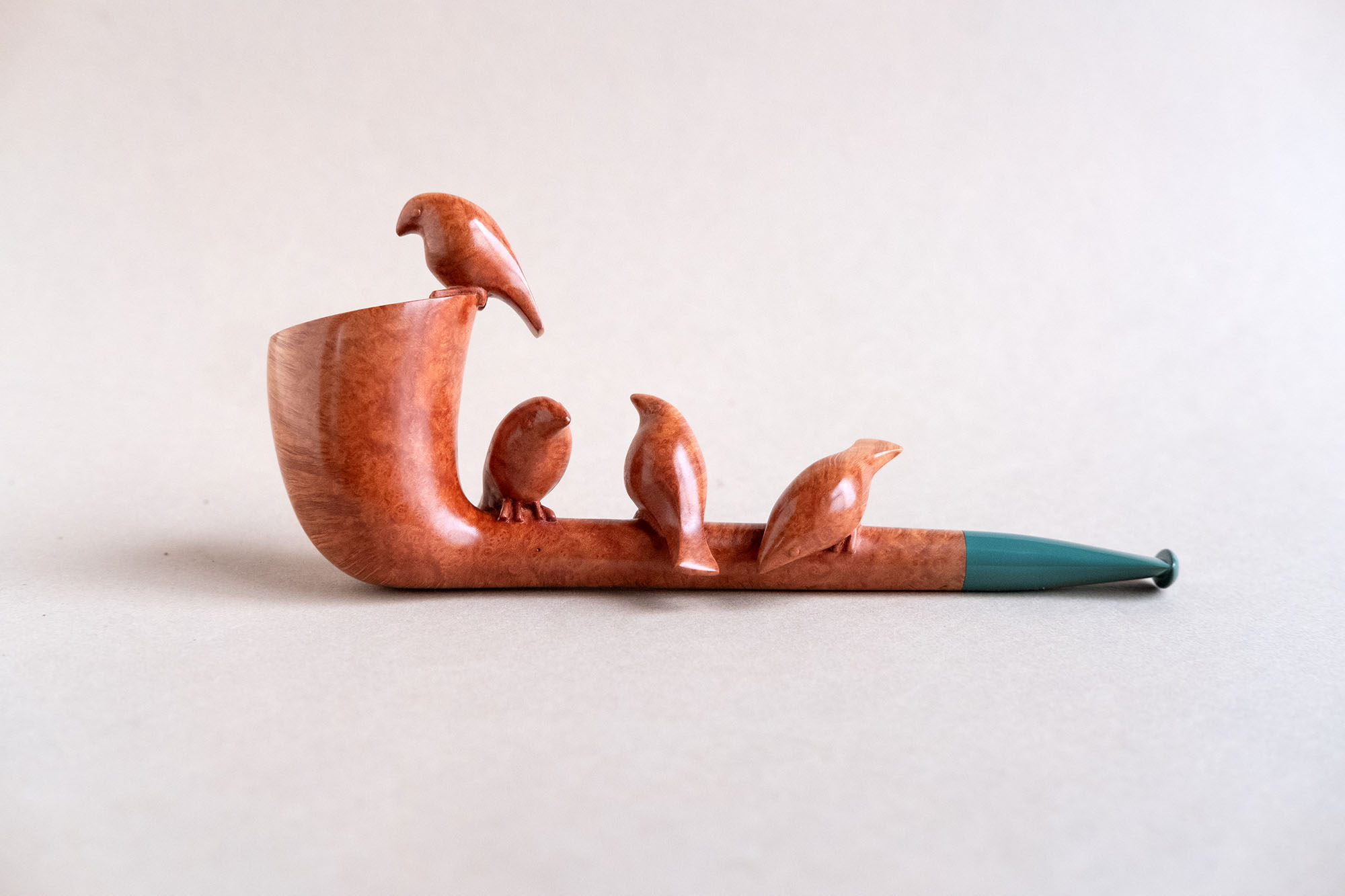 A sculptural smoking pipe handmade of briar, with tiny birds sculpted on it.